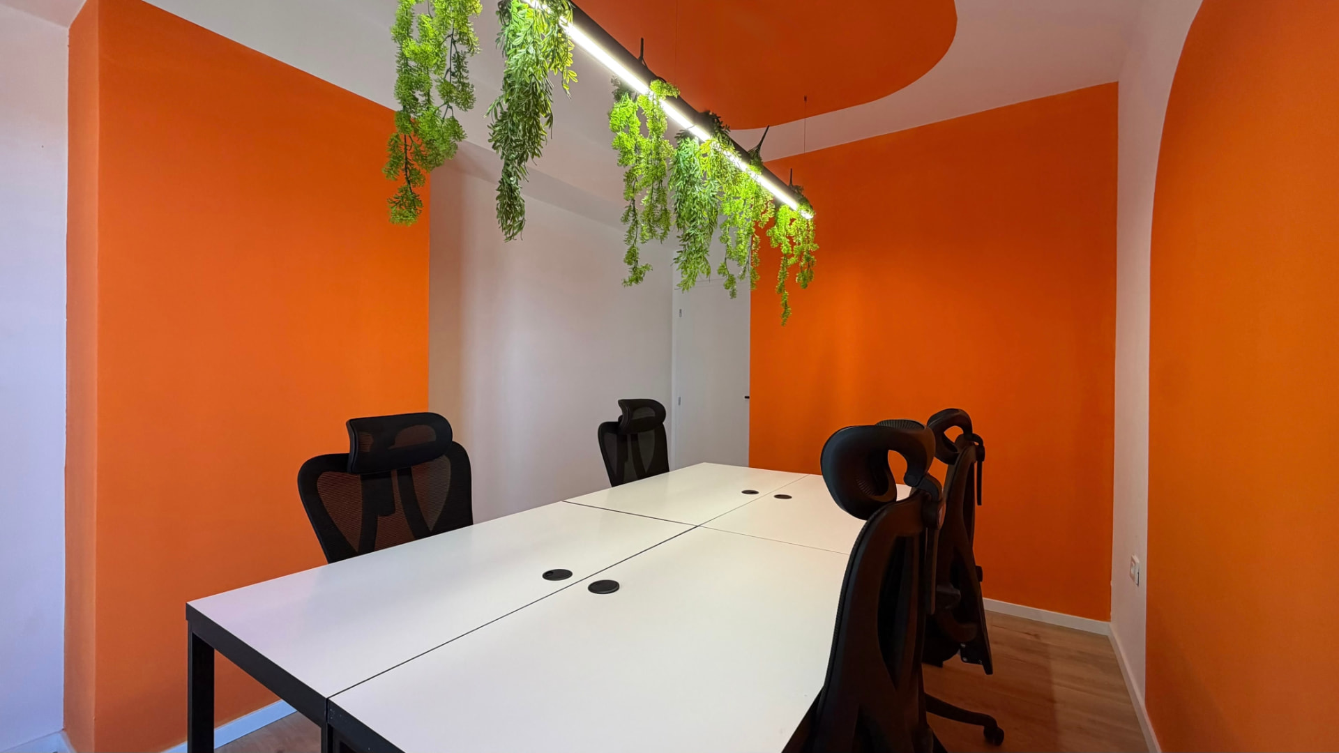 Meeting room at PRN CO-WORK with white desk, black chairs, and a window