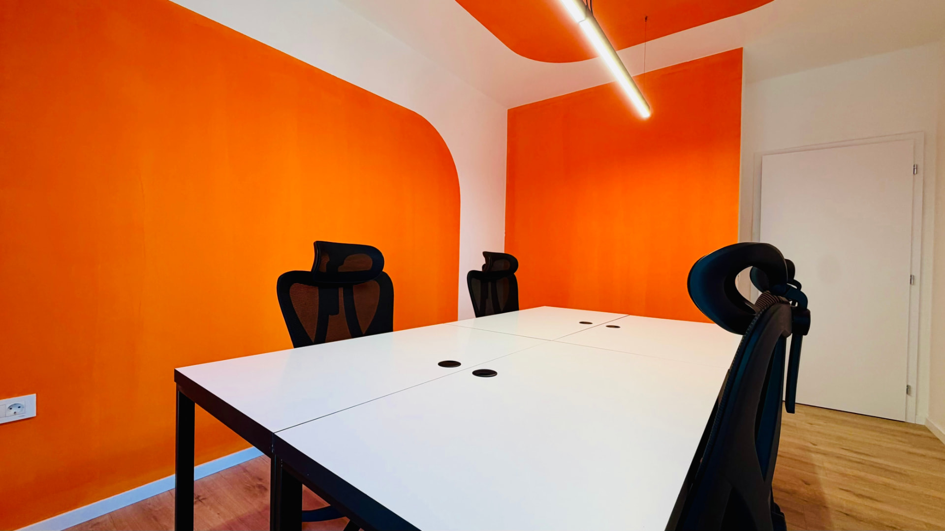 Meeting room at PRN CO-WORK with orange walls, white table, and white door